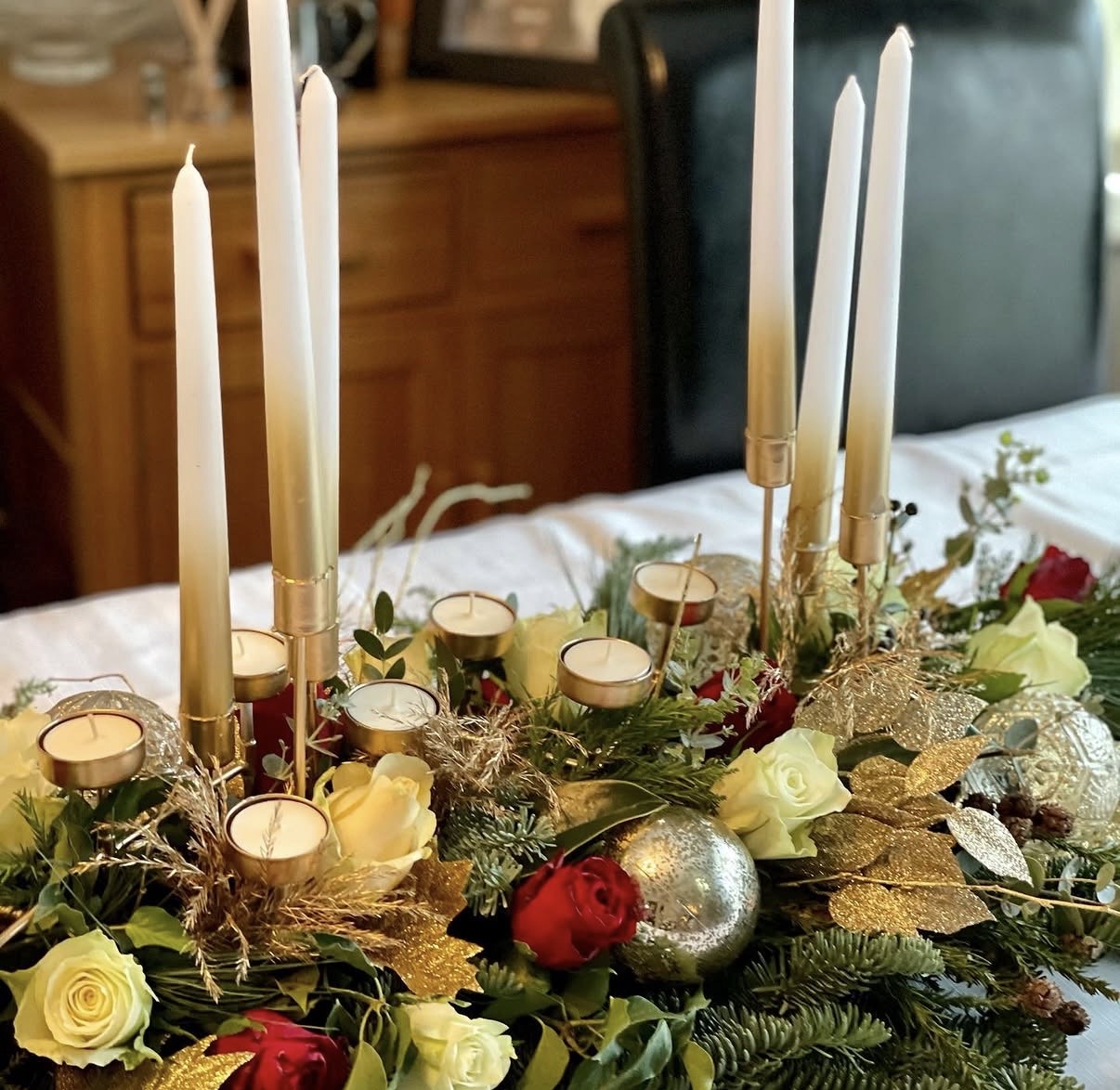 Christmas table centrepiece with candles, roses and gold decorations